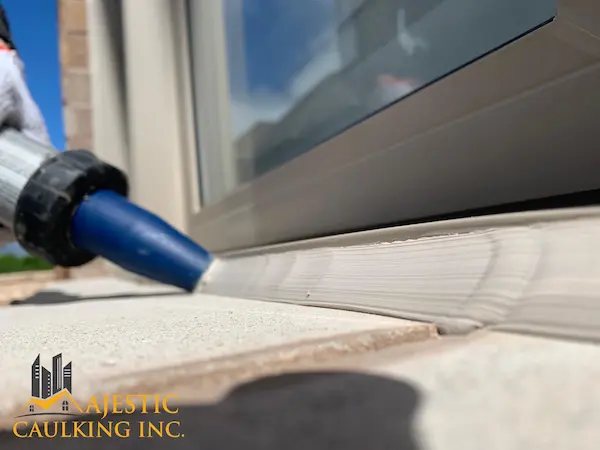 Worker caulking a window